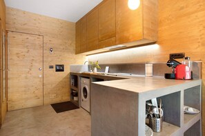 Una cocina moderna con armarios de madera, lavadora integrada y una encimera con electrodomésticos.