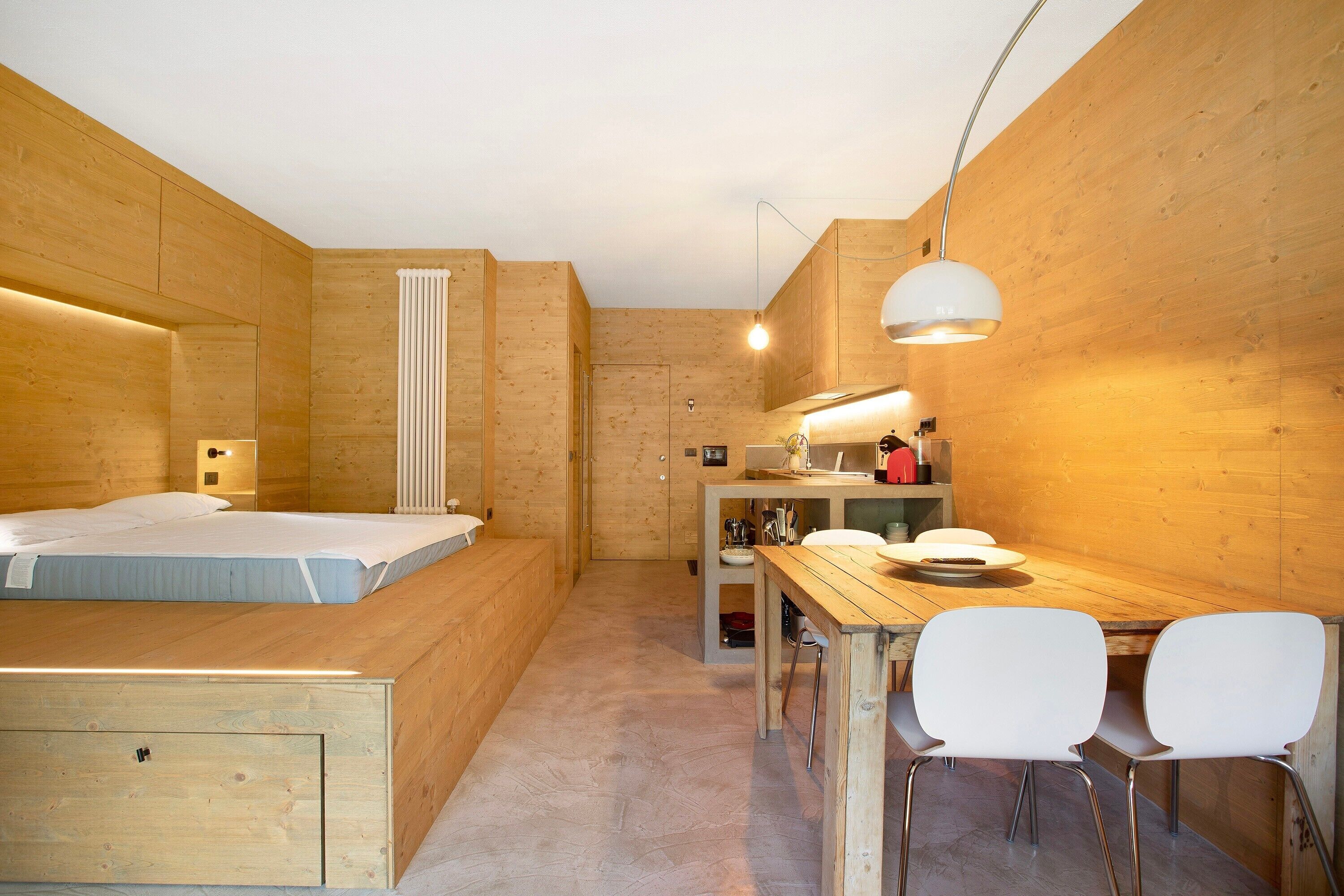 Une pièce de taille modeste comprenant un lit, une petite kitchenette et un coin repas avec des chaises.