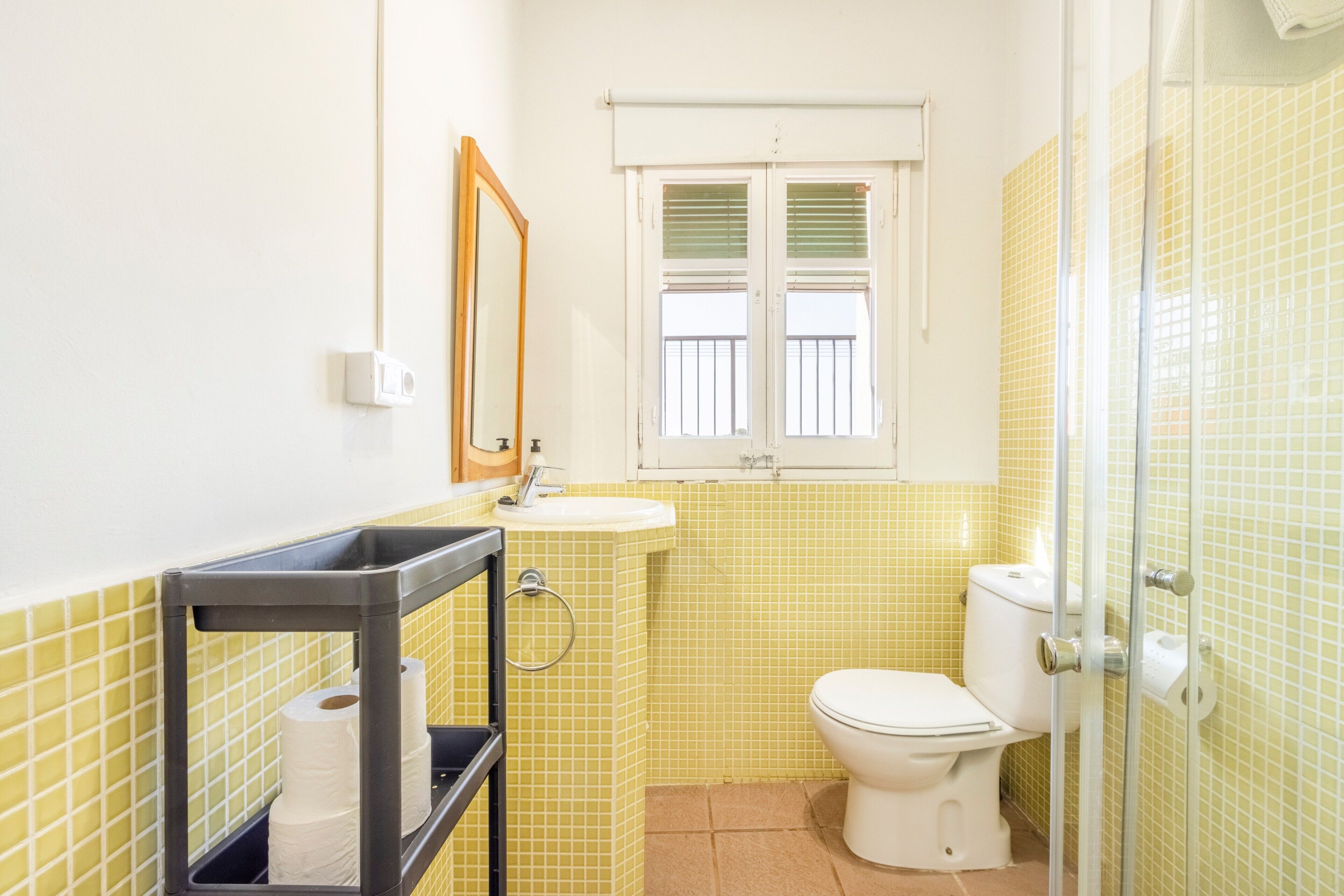 A bathroom with a toilet, sink, and window.