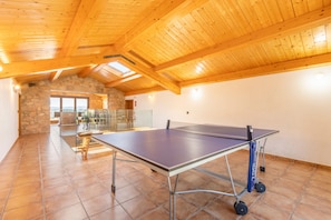 Une table de ping-pong dans une pièce dont le plafond est en pente et les murs en pierre.