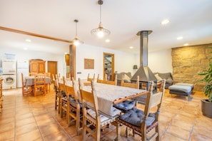 Un vaste espace dédié à la salle à manger, avec une grande table, des chaises en bois et un mur en pierre en arrière-plan.