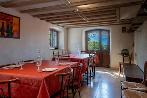 A dining area with wooden tables and chairs, a red tablecloth, and a view of greenery outside. - Gite De Myans for 15 with Garden, Mountain Views, Private Terrace, BBQ & Wi-Fi (Myans)