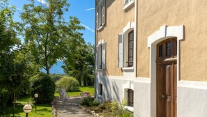 Un bâtiment avec un chemin de gravier, une porte en bois et une vue sur la mer.