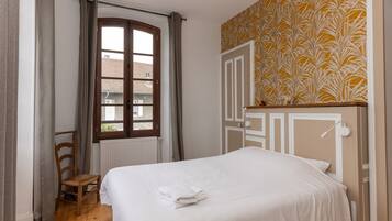 Une chambre à coucher avec un lit, une chaise, une fenêtre et un mur décoré de motifs.