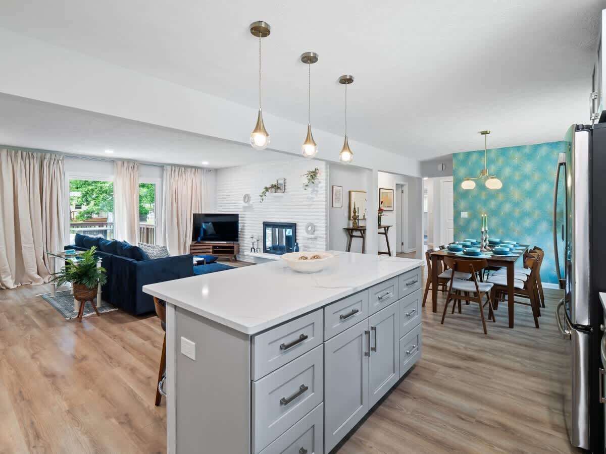 Una cucina moderna con isola centrale, illuminazione a sospensione e zona pranzo con tavolo e sedie.