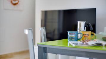 A room with a green table, a coffee maker, and two mugs with text.