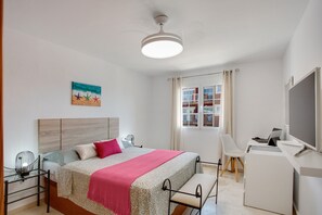 A bedroom with a bed, bedside tables, a desk, a chair, a ceiling fan, and a window with curtains. - Vacation Apartment 'Marysol' with Shared Pool, Private Terrace and Wi-Fi (Caleta de Fuste)