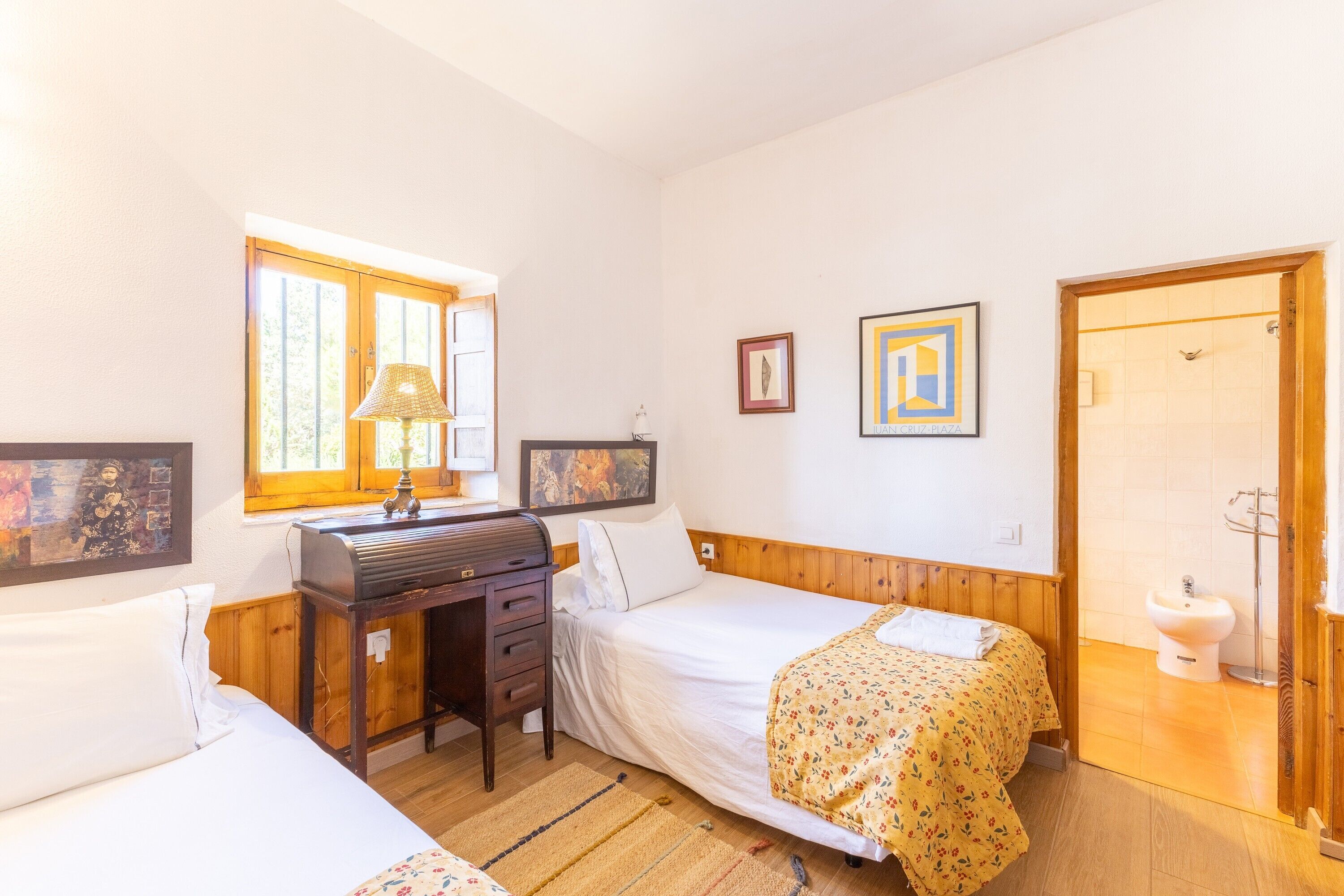 Un dormitorio con dos camas, un escritorio, una ventana y una puerta.
