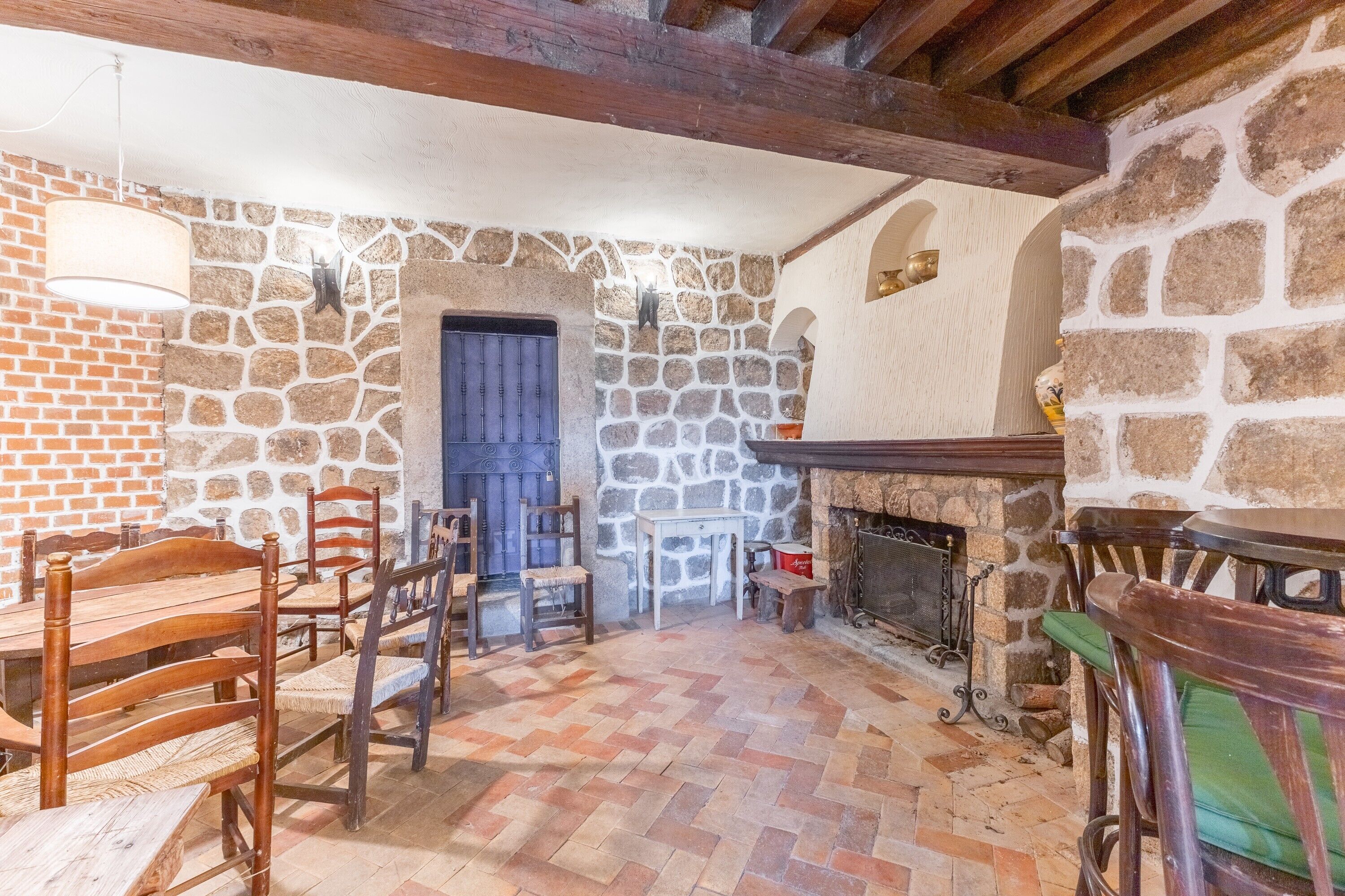 Un interior rústico con pared de piedra, muebles de madera y chimenea.