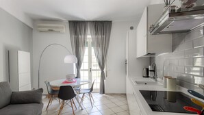 Een kleine keuken met een moderne kookplaat, een eethoek met een tafel en stoelen, en een bank.