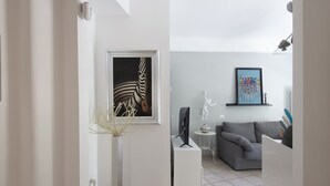 Een moderne woonkamer met een grijze bank, een flatscreen-tv en abstracte kunst aan de wanden.