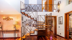 Un escalier doté d’une rampe métallique aux motifs géométriques, de marches en bois et d’une moquette rouge.