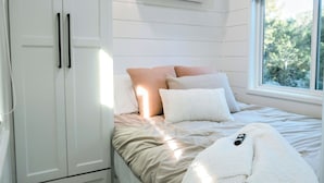 Un dormitorio con cama, armario blanco y equipo de aire acondicionado.