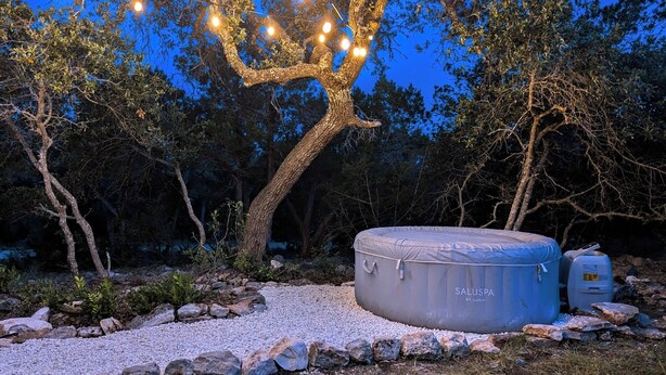 Un árbol con luces, una bañera de hidromasaje y una zona rocosa.
