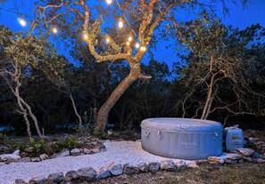 Un arbre décoré de guirlandes lumineuses, un jacuzzi et une zone rocheuse.