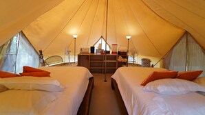 Eine Zelthütte mit zwei Betten, einem Schreibtisch und einem Ventilator.