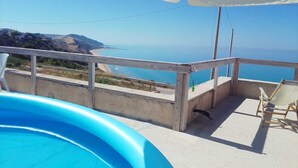 Zona de piscina con vista al mar y terraza de madera.