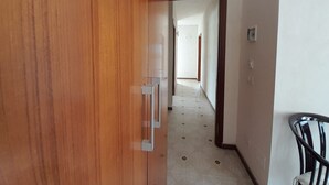 Ein Korridor mit einer Holztür, Fliesenboden und einem Stuhl.