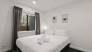 Una habitación de hotel con una cama, una ventana con cortinas y dos cuadros en la pared.
