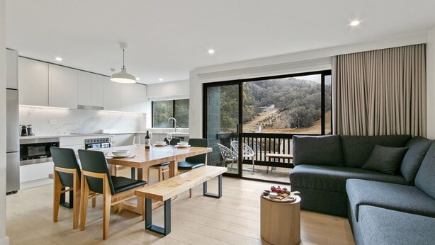 Una cocina moderna con comedor, un balcón con vistas al campo y una sala de estar con sofá.