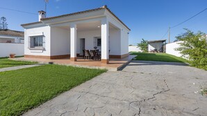 A single-story house with a covered patio, a small garden, and a paved driveway.