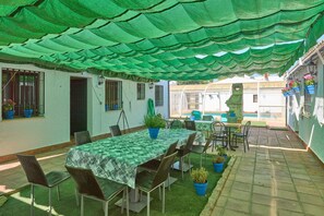 An outdoor patio area with a table and chairs, covered by a green canopy, and potted plants. - Rivero Rural Country House - Private and Indoor Pool, 10 Bedrooms, 22 Guests (Rivero de Posadas)