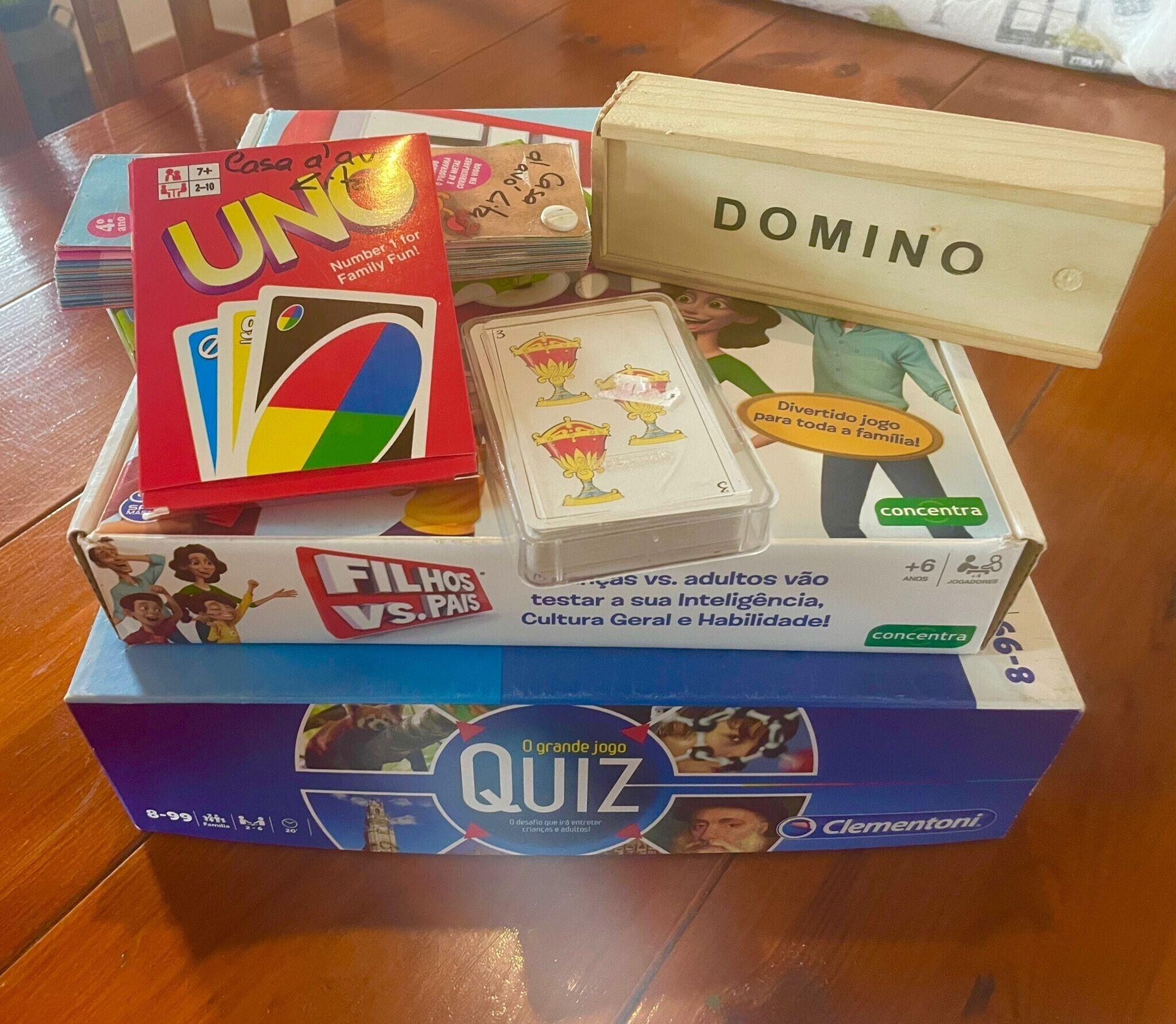 A game box labeled 'QUIZ' with 'Clementoni' branding, a 'UNO' game box, and a 'DOMINO' set.