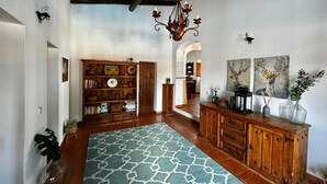 A spacious living area with a patterned rug, wooden furniture, and artwork on the walls.