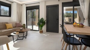 Uma sala de estar moderna com sofá, mesa de centro, mesa de jantar com cadeiras, planta em vaso e porta de vidro deslizante para área externa.