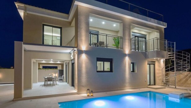 Ein modernes Haus mit zwei Etagen, einem Schwimmbad, Sitzgelegenheiten im Freien und einem Balkon.
