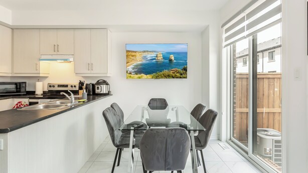 A modern kitchen with a dining area, featuring a large window with a coastal view. - Chic Retreat Near Niagara Falls (Niagara Falls)