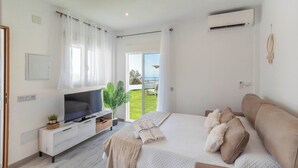 Un dormitorio moderno con una cama grande, un televisor, una planta y vistas a un espacio exterior verde.