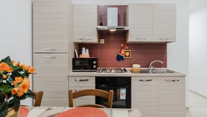 A modern kitchen with light wood cabinets, a microwave, stove, and a sink. - Holiday Home 'Iris Castelvetrano' with Wi-Fi and Air Conditioning (Castelvetrano)