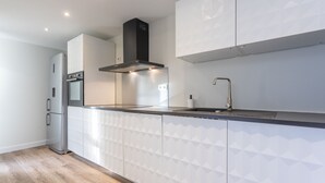 Una cocina moderna con horno empotrado, armarios de acero inoxidable, campana extractora negra y pileta de acero inoxidable.