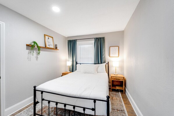 Una camera da letto con un letto, due comodini, una finestra con tende e mensole a parete con oggetti decorativi.
