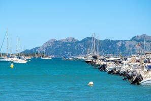 Un port de plaisance avec des bateaux amarrés, un ciel dégagé et des montagnes en arrière-plan.
