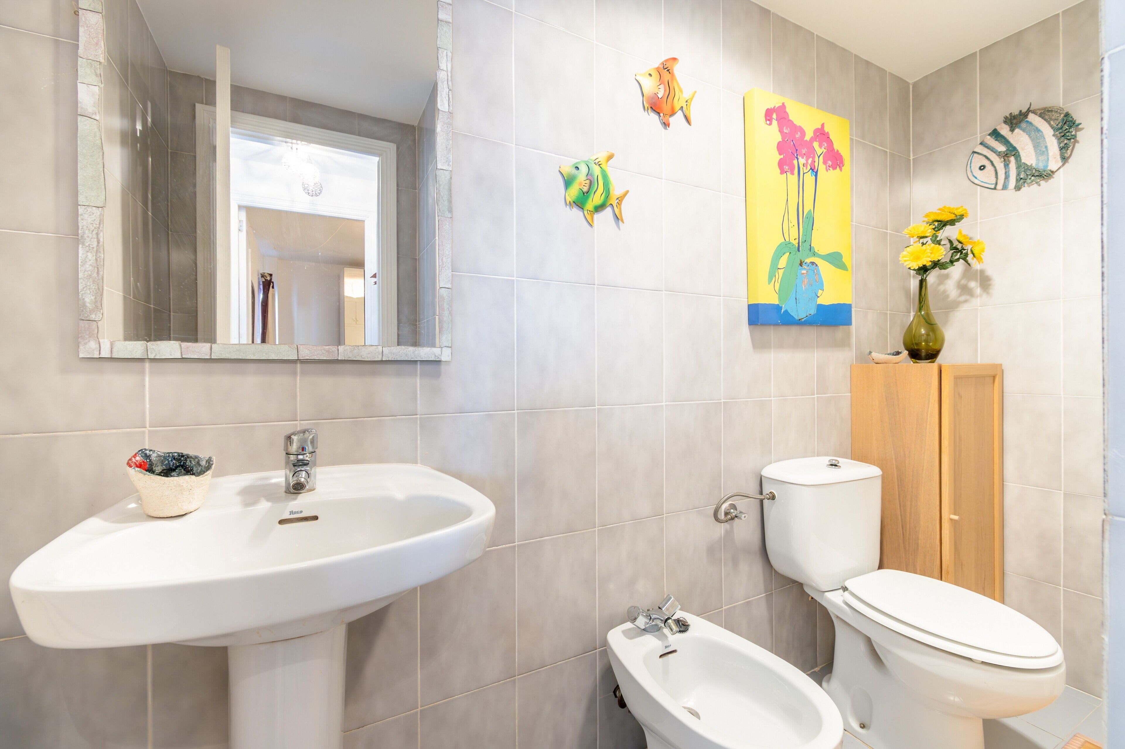 A bathroom with a sink, toilet, bidet, and a mirror.