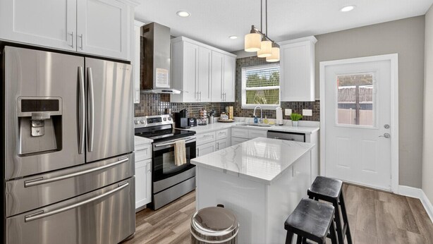A modern kitchen with stainless steel appliances, a central island, and pendant lighting.