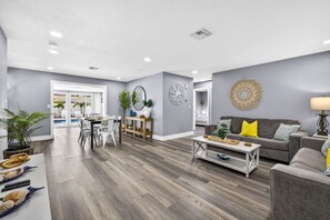 Un salon moderne comprenant un coin repas, avec des murs gris, un plancher en bois et une vue sur un balcon.