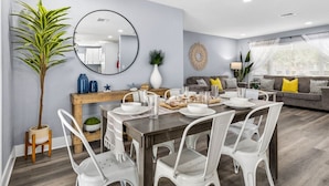 A modern living room with a dining area, a large mirror, and a potted plant. - Family Pool Home | Game Room + Fire Pit | Largo (Largo)