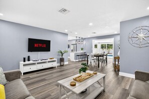 Un salon moderne doté d’un téléviseur à écran plat, d’un coin repas et offrant une vue sur l’extérieur.