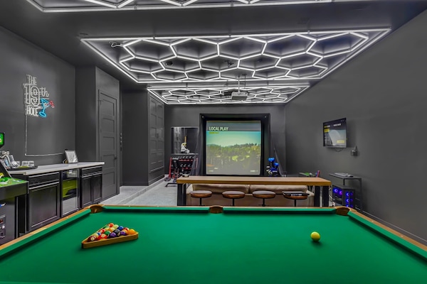 Garage conversion with golf simulator, billiards table, bar area with beer fridge, Golden Tee arcade game, TV with cable, workout equipment, and plenty of seating!