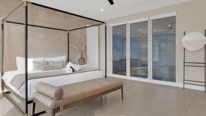A modern bedroom with a four-poster bed, a bench, and a large window with a view. - Heated Pool & Spa, Golf Simulator, Billiards (Scottsdale)