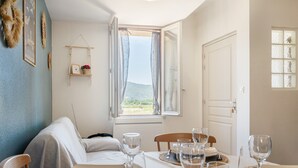 A dining area with a table set for four, a view of the outdoors, and a door to the right.