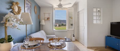 A dining area with a table set for four, a sofa, and a television in the corner.