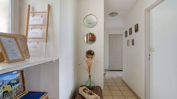 A hallway with a wooden ladder, a mirror, framed pictures, and a wicker basket with a book.