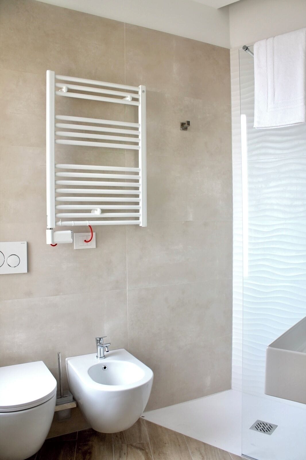 Ein modernes Badezimmer mit integriertem Bidet, Handtuchhalter und Dusche.
