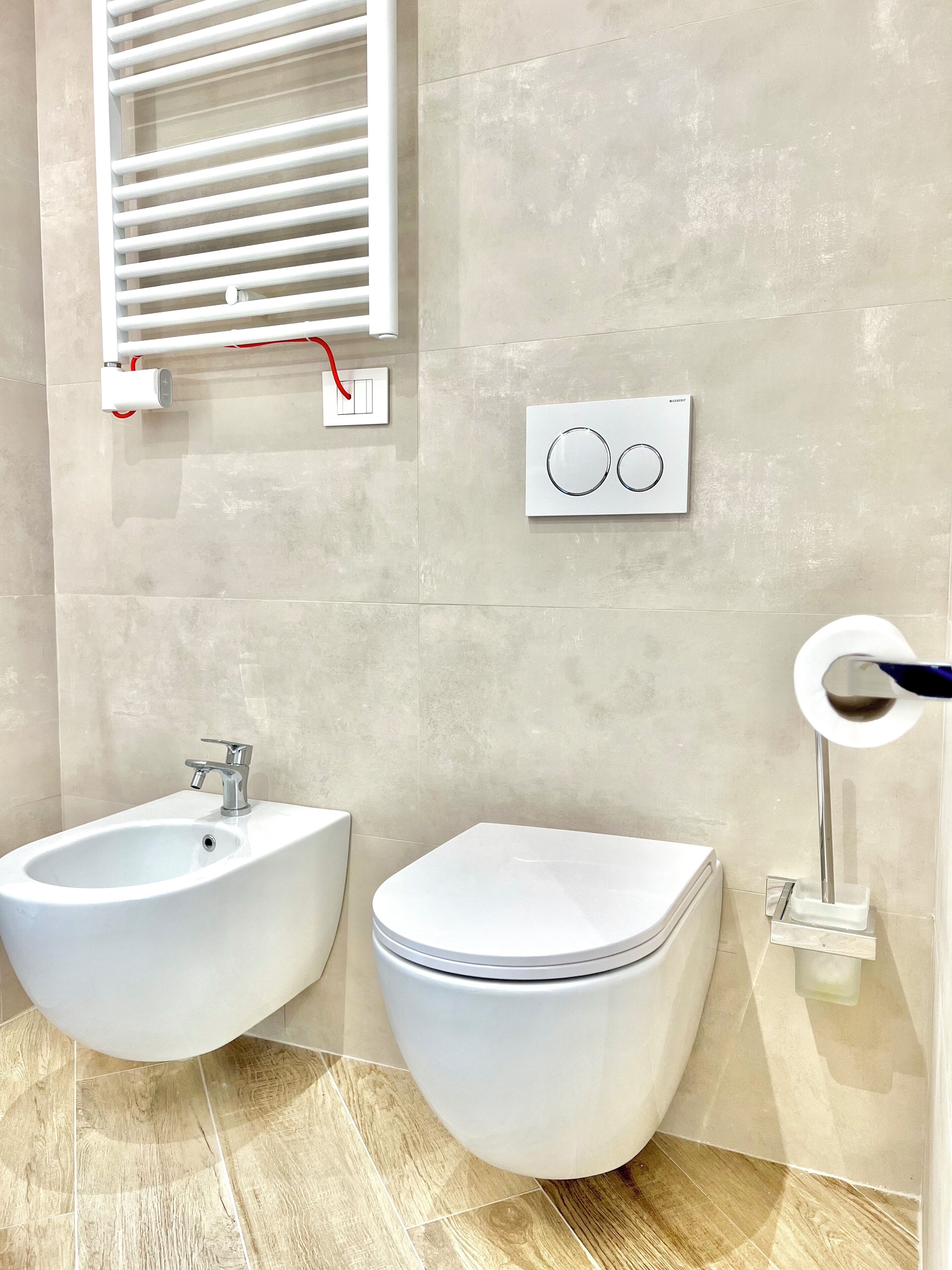 Un bagno con bidet, servizi igienici e pannello di controllo del bidet a parete.