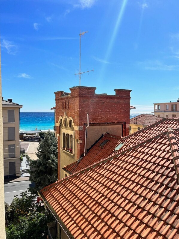 A building with a red-tiled roof and a brick tower with arched windows.