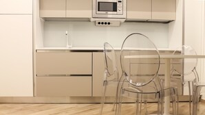Cozinha moderna com micro-ondas, cadeiras transparentes e piso de madeira.